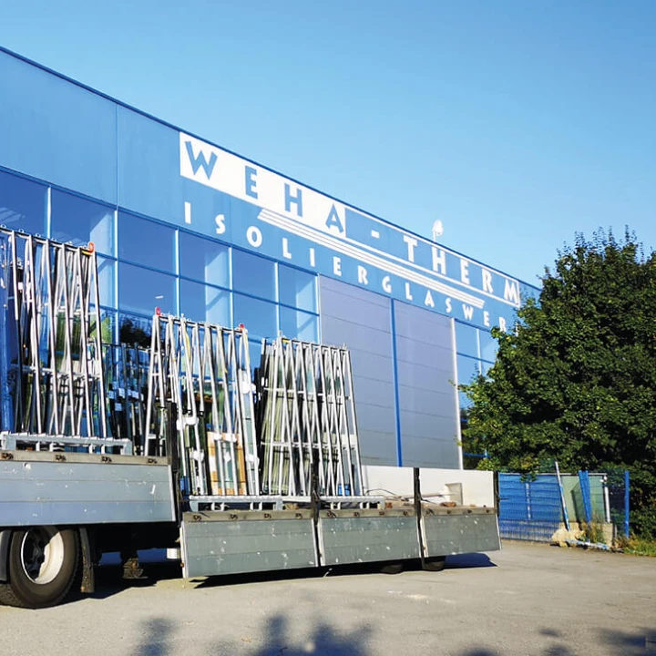 box-id_success-story_weha-therm_truck-with-loaded-glass-transport-racks LKW mit Glas-Transportgestellen vor Produktionshalle von Weha-Therm