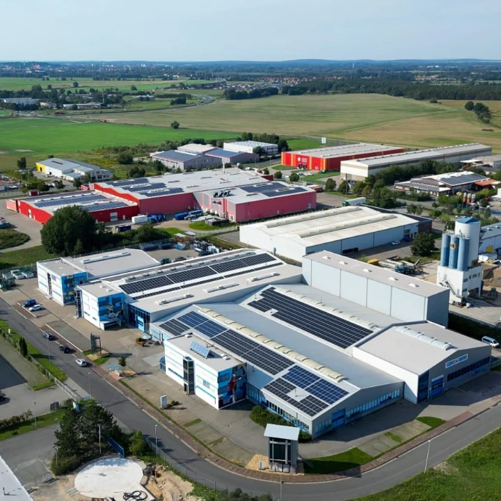 boxi-id_success-story_metallbau-windeck_production-hall Luftaufnahme eines Industrieareals mit Produktionshallen und Photovoltaik-Dächern im Grünen